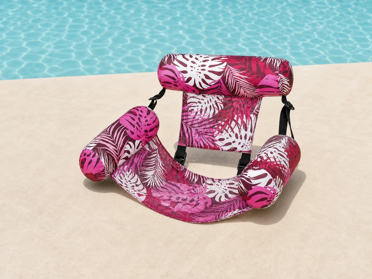 Pink tropical-print Poolora Float Chair beside a swimming pool